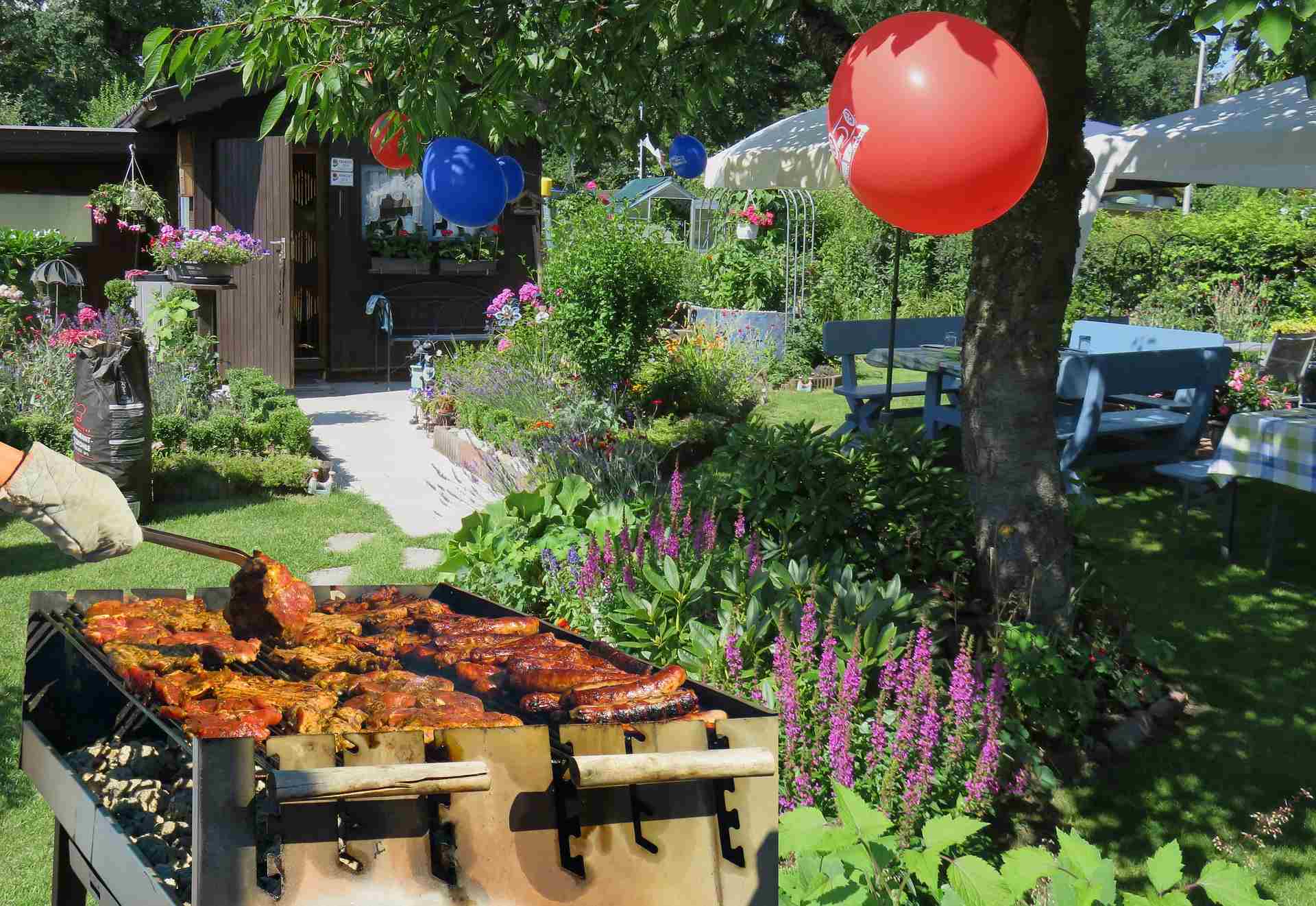 Blick auf einen Garten, wo ein Griller mit Fleisch steht